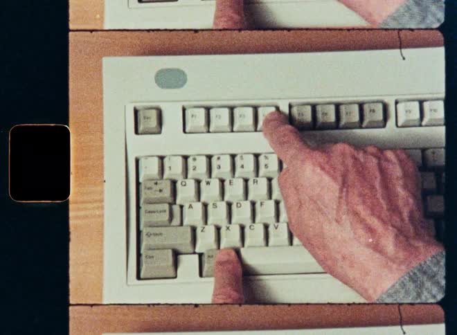 An overhead shot captures a person typing on a classic, beige computer keyboard, presented with an authentic film strip border