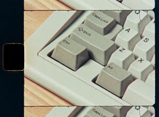 A person's hand presses the keys Ctrl, Alt, and Z for the undo command on a retro computer keyboard, presented with a vintage film border