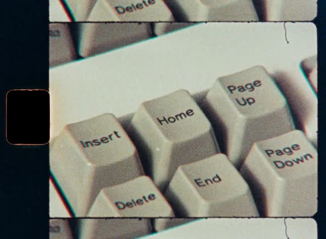 A close-up shot on retro film of a finger pressing the home key on a vintage computer keyboard