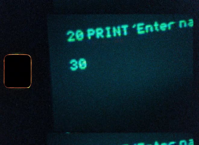 A close-up shot of BASIC computer programming code being typed on a vintage CRT monitor