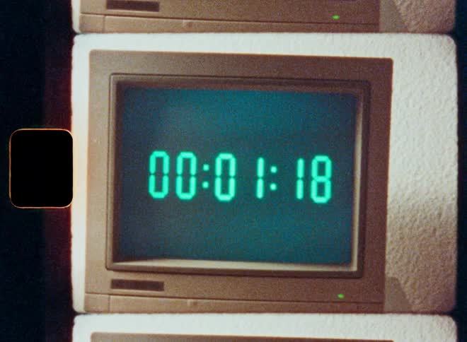 A retro digital timer on an old computer monitor counts down from five minutes to zero in a vintage film style