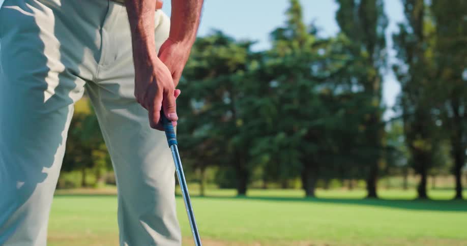 Detailed slow-motion close-up of a male golfer's hands as he grips his club on a sunny day