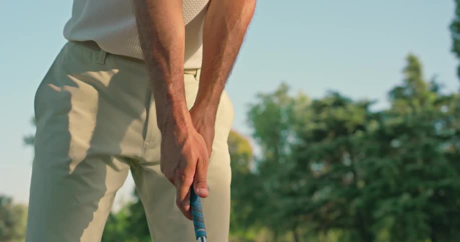 Slow motion close-up of a golfer adjusting his grip on a golf club on a sunny day