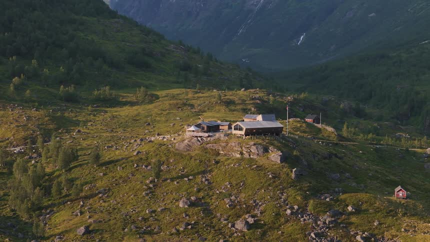 The Fondsbu tourist cabin sits nestled in the vast, green landscape of the Jotunheimen mountains in Norway