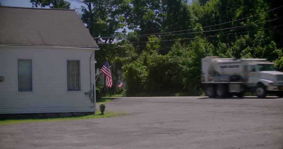 A truck drives past a home on a sunny day