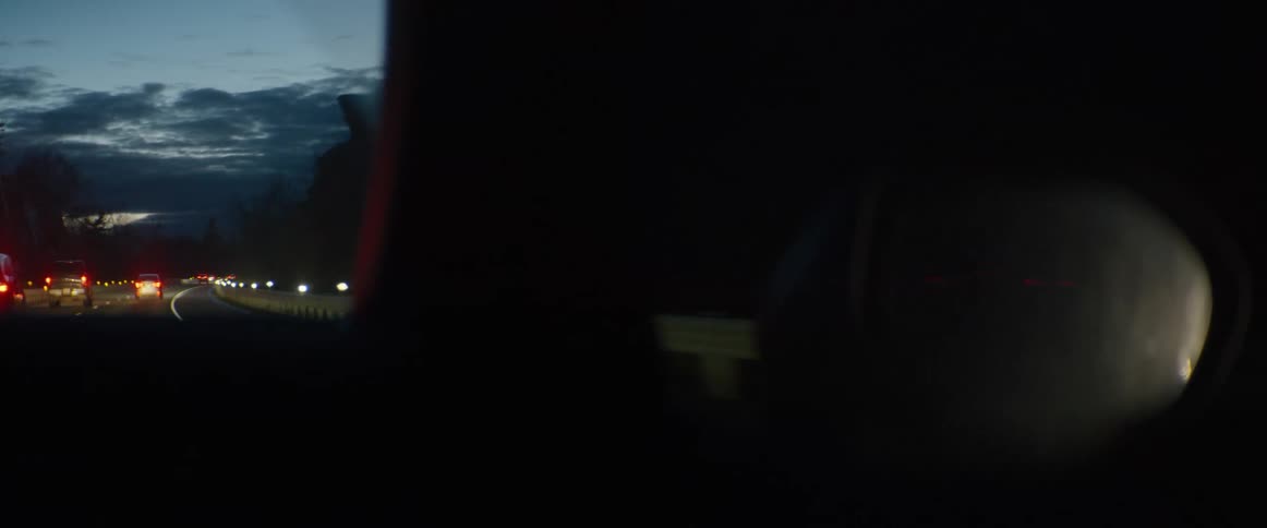 A moody passenger-side view of traffic lights on a dark highway at dusk
