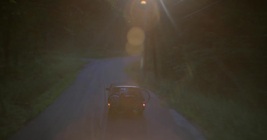 Vehicle driving down a country road carrying bicycles on its rear at sunset