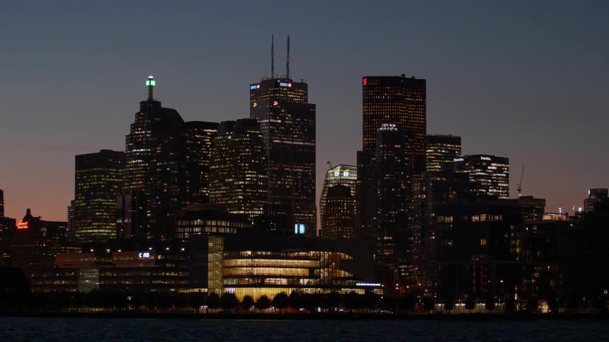 The illuminated skyline of downtown Toronto glitters at dusk as seen from across the water
