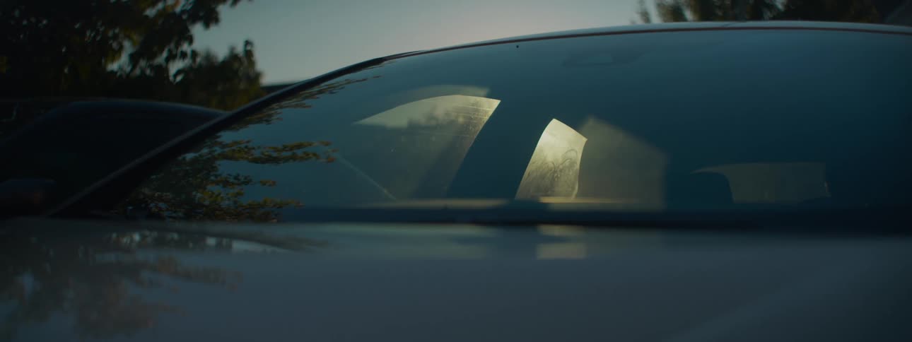 Moody close-up shot of a car windshield with a beautiful sun flare at golden hour