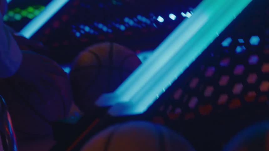 A young man intensely playing a neon-lit arcade basketball game with his friends