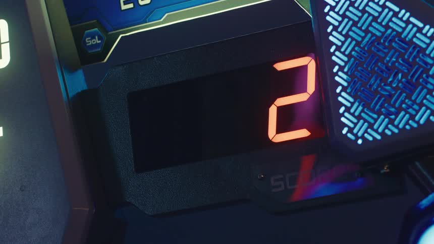 A close-up of a futuristic arcade game's digital score counter flashing numbers before resetting to zero