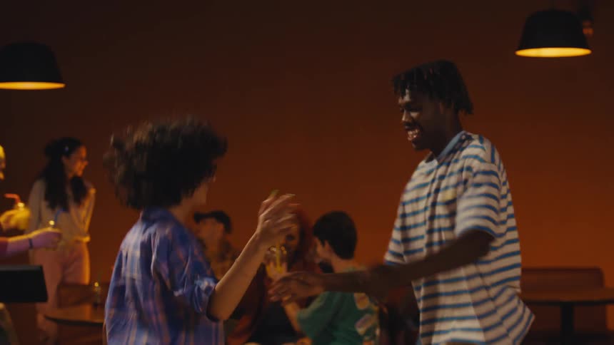 An ecstatic young man celebrates a winning bowling throw with a victory dance before joining his friend for a joyful high-five and handshake