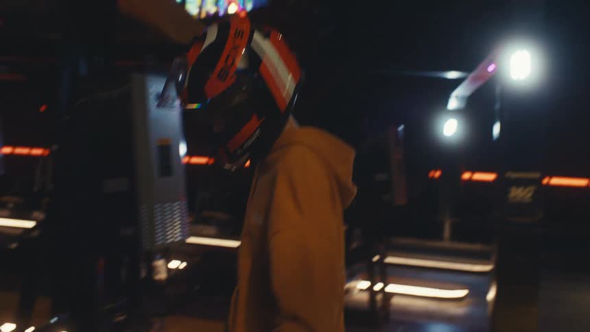 A young person puts on a racing helmet before getting into their go-kart at an indoor track