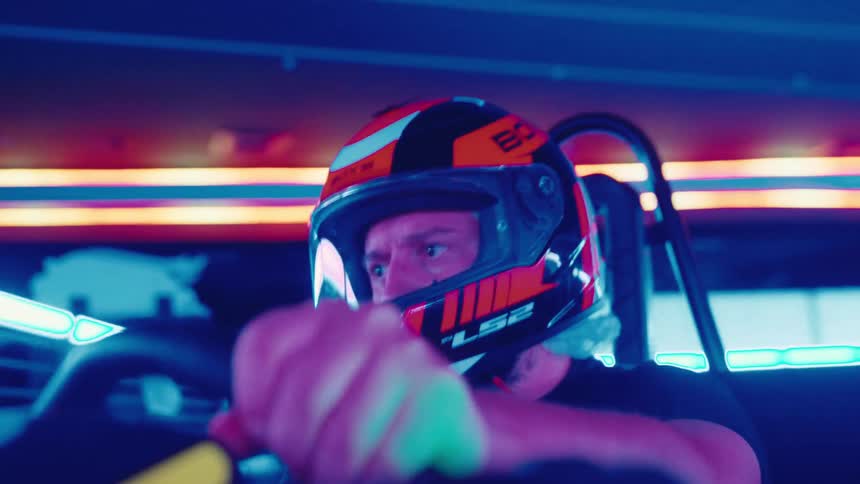 Close-up of an intense go-kart driver in a helmet racing at speed on a futuristic track with flashing neon lights