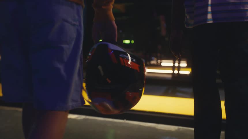 Close-up slow motion shot of a person carrying a racing helmet while walking towards an indoor go-kart track