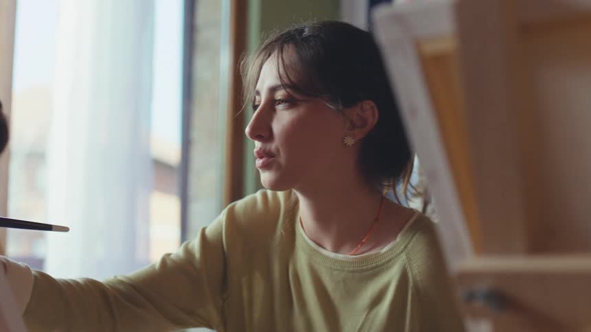 A slow-motion pan reveals women of different generations engaged in a painting class