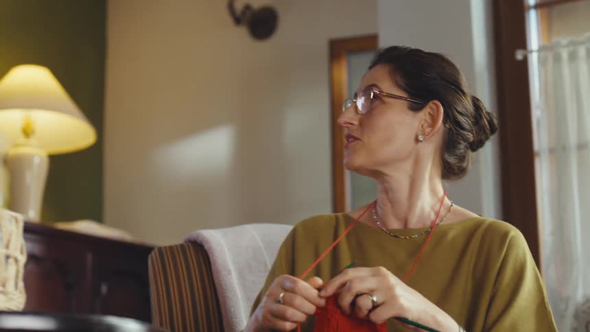 Three generations of women, a grandmother, mother, and granddaughter, bond while knitting together in a cozy living room