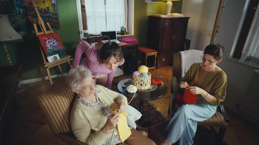 A curious young woman joins her mother and grandmother for a quiet afternoon of knitting and family bonding at home