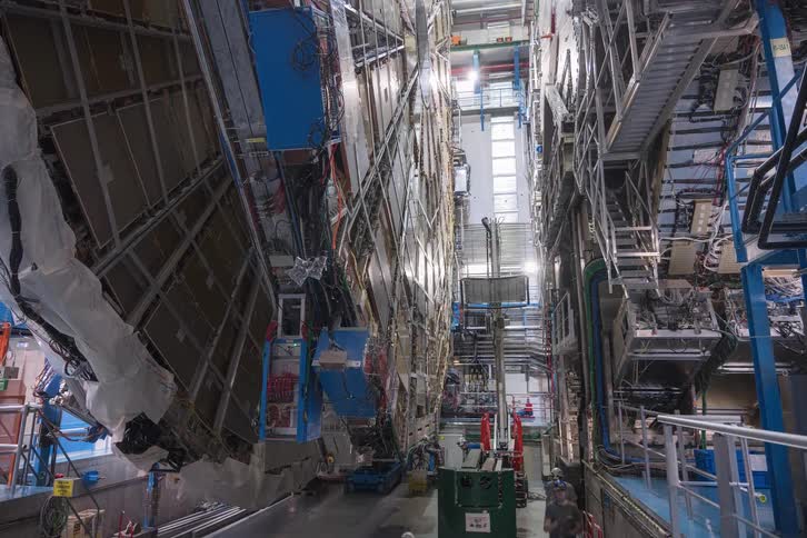 High-angle timelapse reveals the intricate process of engineers assembling a massive particle detector within a vast scientific research facility