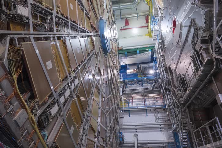 A wide-angle, slow pull-back shot reveals the intricate and massive structure of a particle accelerator at a research lab