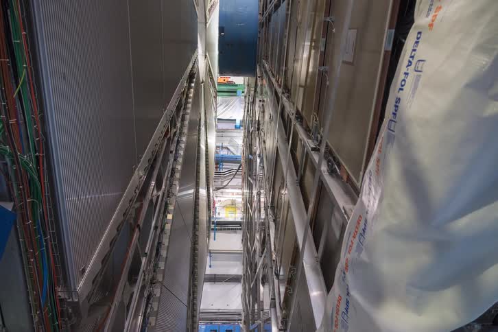 Vertical timelapse reveals engineers and technicians working to assemble and close the massive sections of a particle accelerator