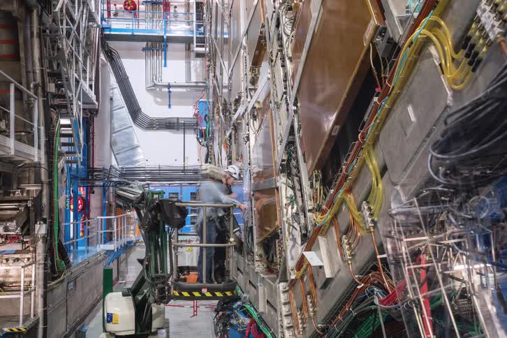 Timelapse of engineers working on the intricate wiring and machinery of a particle accelerator at a scientific research facility
