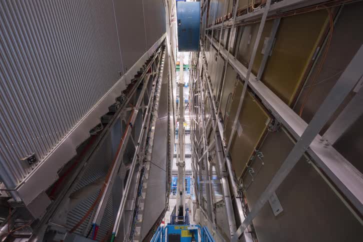Vertical time-lapse shows the complex process of assembling the massive components of a particle detector at a high-tech research laboratory