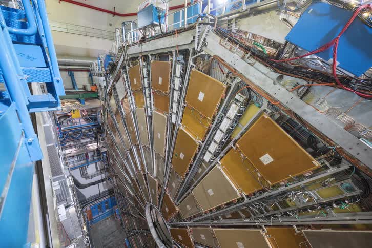 Static high-angle view of the immense and complex machinery of a particle detector inside a scientific research laboratory