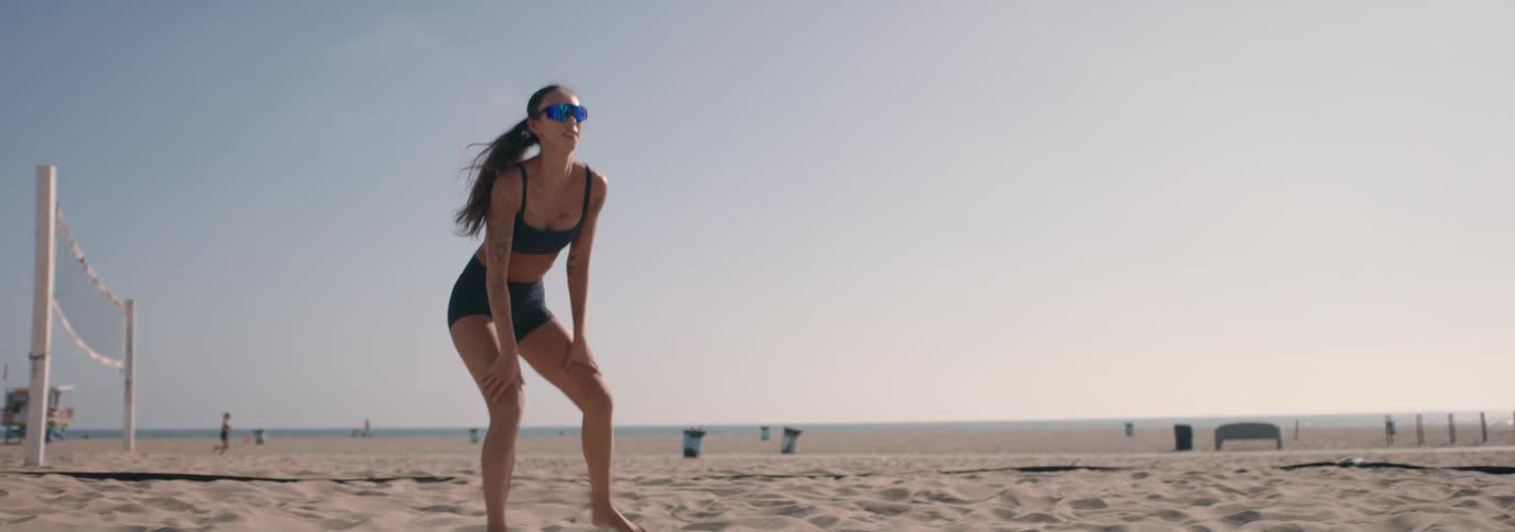 Slow motion shot of a woman in athletic gear playing beach volleyball and making a spectacular dive in the sand