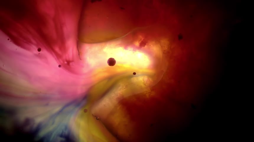 Psychedelic swirls of red and yellow ink create an abstract cosmic scene with floating dark orbs