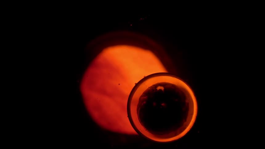 A crucible glows with intense orange heat as the material inside begins to melt against a dark background