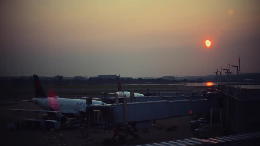 A stunning time-lapse captures the sun rising over a busy airport tarmac as airplanes prepare for departure