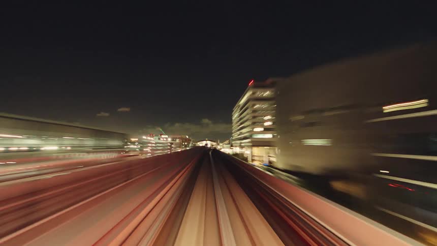 A stunning point-of-view hyperlapse of a high-speed monorail journey through the brilliantly lit cityscape of Tokyo at night