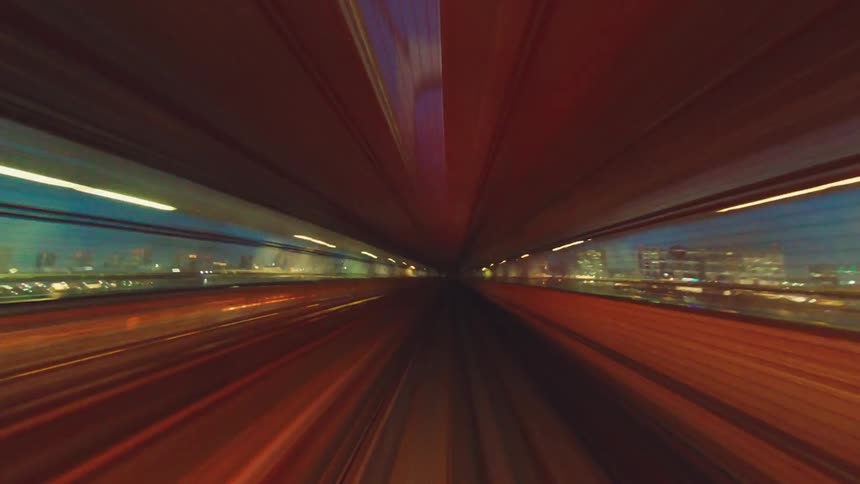 A high-speed, point-of-view time-lapse of a monorail racing through a futuristic city at night, with light trails streaking past