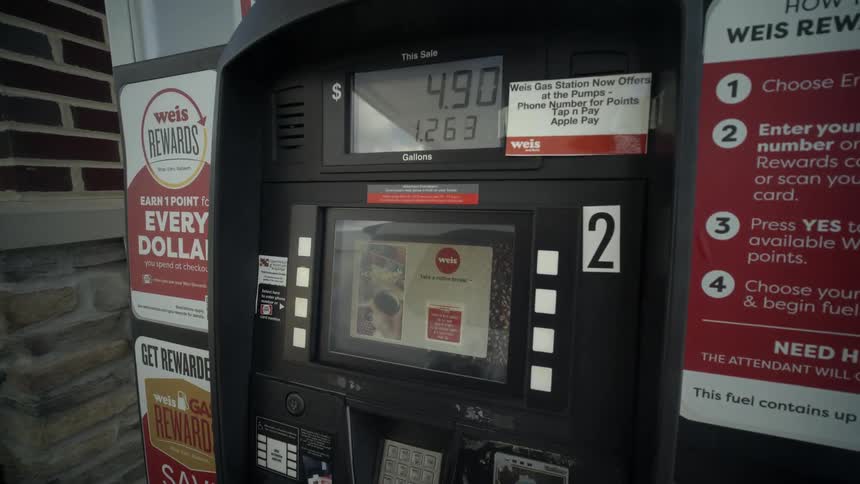 A first-person view of pumping gasoline into a white vehicle at a gas station, showing the digital display of the price and gallons increasing
