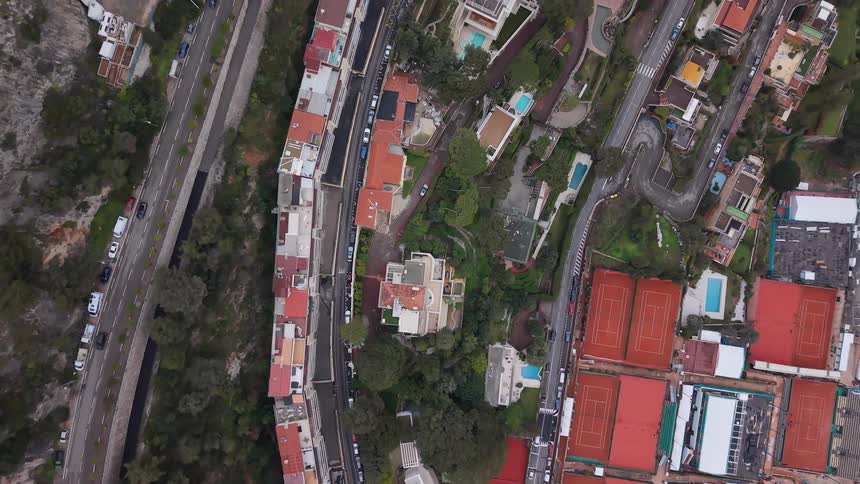 A top-down aerial view slowly reveals the luxurious hillside residences, winding roads, and tennis courts of Monaco