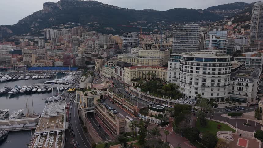 An aerial view pulls back to reveal the cityscape and famous harbor of Monte Carlo, Monaco on a cloudy day