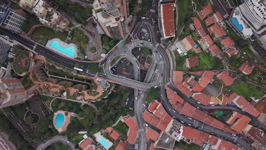 A slowly rotating top-down aerial shot captures traffic flowing through a complex and intricate road intersection in the heart of Monaco