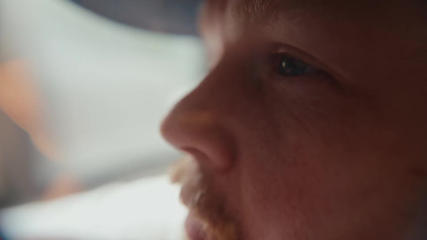 An intimate close-up profile shot of a thoughtful man's face as he looks down in contemplation