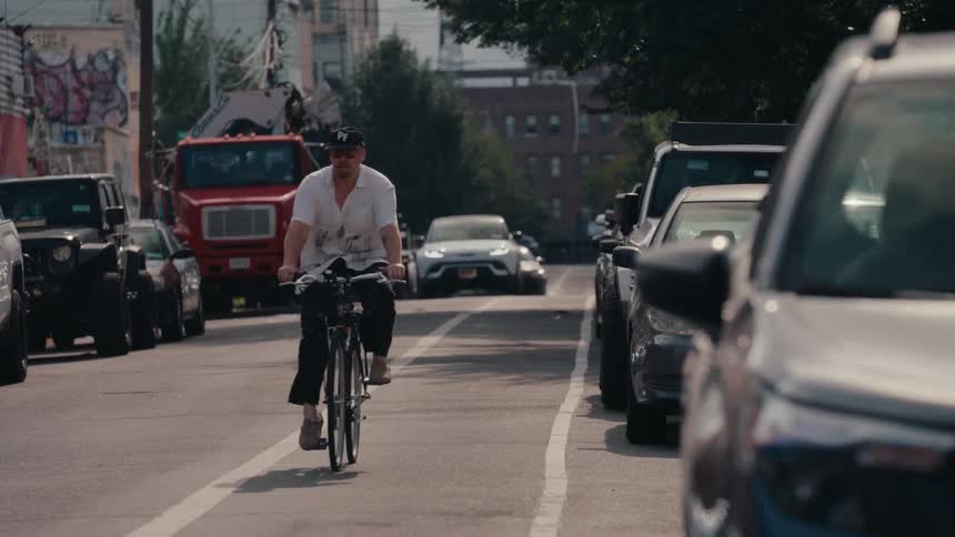 A man rides his bike in slow motion down an urban street in a dedicated bike lane