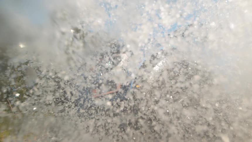 A powerful Ford Raptor truck plows through water in slow motion, creating a huge splash that engulfs the camera lens