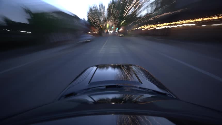 Energetic hyper-lapse POV from a car driving through a vibrant city at night, with streaking light trails showing the speed and motion
