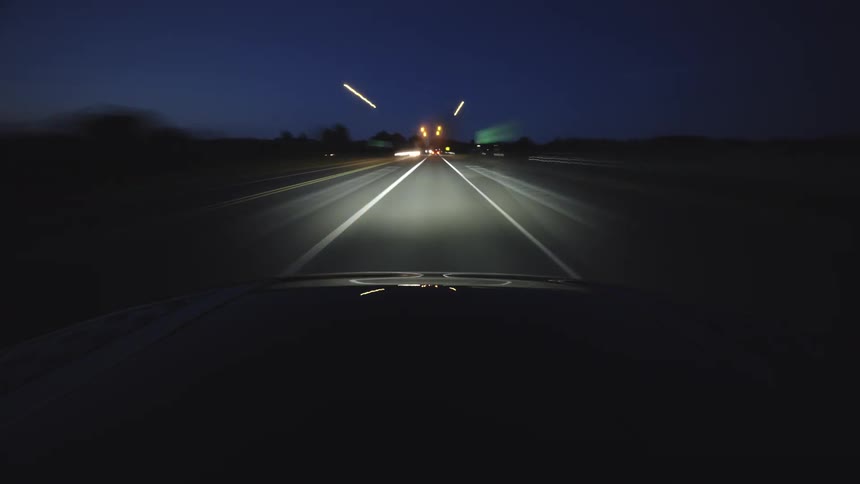 A fast-paced time-lapse from a car's perspective driving through city streets and country roads at night with mesmerizing light trails