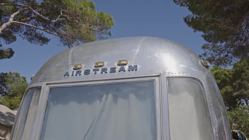 Low angle shot of a vintage Airstream trailer parked in nature on a clear summer day