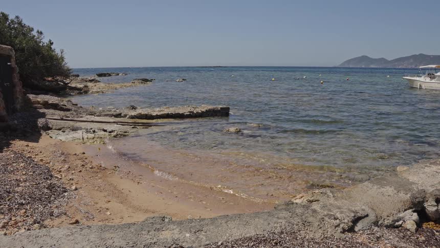 A serene view of a small rocky beach cove with clear water gently lapping the shore on a sunny day