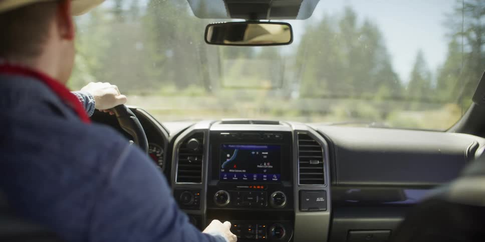 From the backseat, a cowboy gets into his truck, starts the engine, and uses the GPS for navigation