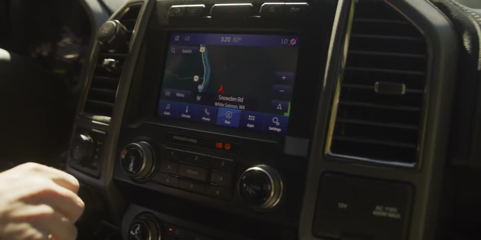 A driver interacts with the GPS navigation system on the touch screen display of a modern truck, zooming on the map and dismissing a text message notification