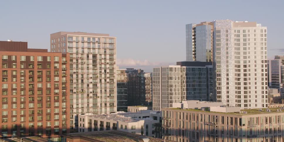 A slow reveal of a modern city's diverse architecture as the camera pans across apartment buildings and offices during a sunny late afternoon