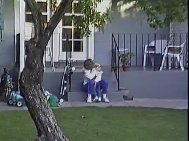 A mother and her young son share a tender hug on the porch steps of their home in this nostalgic home video
