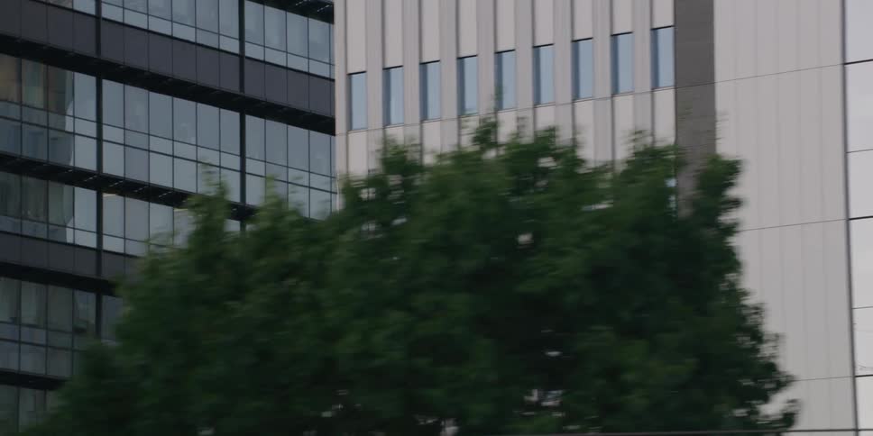 Close-up tracking shot of a modern office building's reflective glass facade in a city